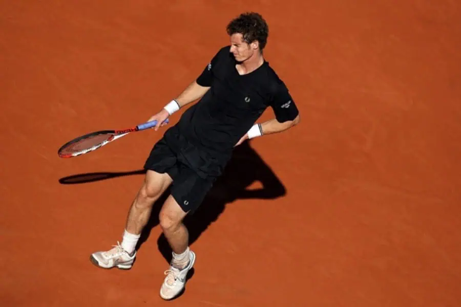 Joueur de tennis en pleine frappe sur terre battue